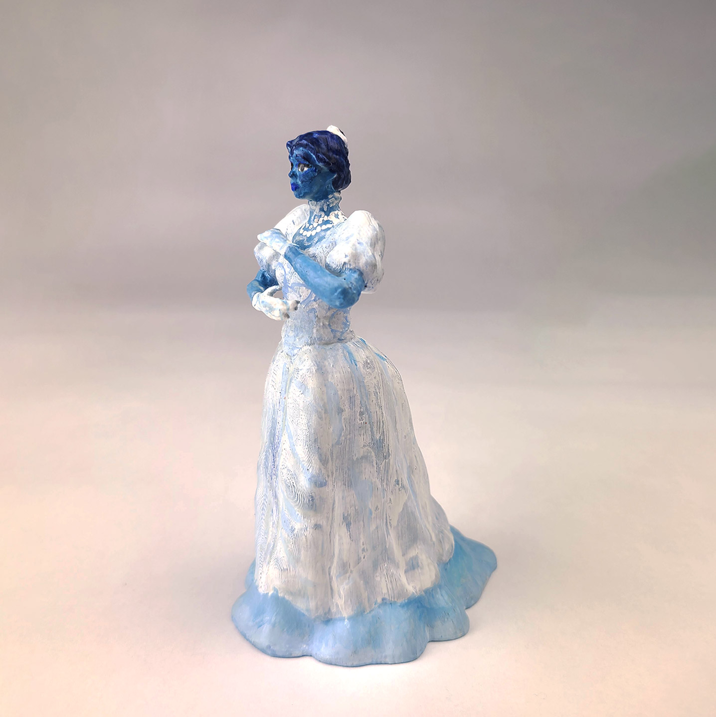 A photograph of a painted 3d print of a blue woman in a large dress